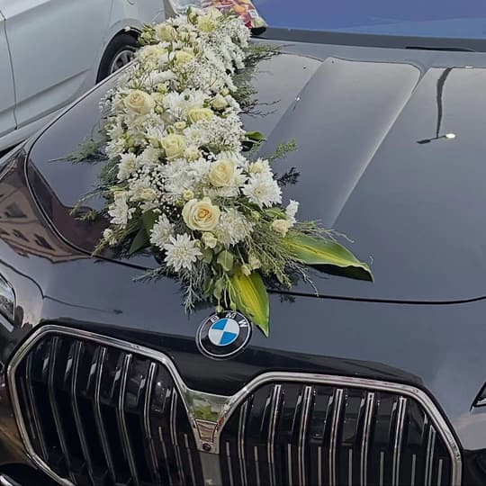 سيارة بي إم دبليو سوداء عليها تنسيق ورد أبيض وجوري كريمي